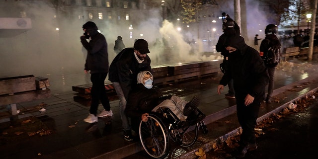 Demonstrators leave the Place de la Republique among tear gas after a demonstration, Dec. 5, in Paris. Thousands marched in protests around France on Saturday against a contested security bill with tensions quickly rising at the Paris march as intruders set fire to several cars, broke windows and tossed projectiles at police. (AP Photo/Lewis Joly)