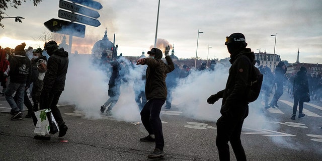 A man throws a bottle at the police during a demonstration in Lyon, central France, Dec. 5. Thousands marched in protests around France on Saturday against a contested security bill with tensions quickly rising at the Paris march as intruders set fire to several cars, broke windows and tossed objects at police. (AP Photo/Laurent Cipriani)