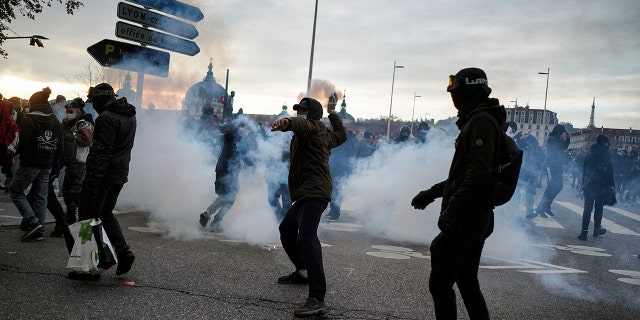 A man throws a bottle at the police during a demonstration in Lyon, central France, Dec. 5. Thousands marched in protests around France on Saturday against a contested security bill with tensions quickly rising at the Paris march as intruders set fire to several cars, broke windows and tossed objects at police. (AP Photo/Laurent Cipriani)