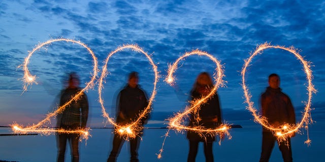  Four people write the year 2020 with sparklers into the evening sky at the stand of the Baltic Sea island of Rügen (shot with long time exposure).  (Photo by Patrick Pleul/picture alliance via Getty Images)