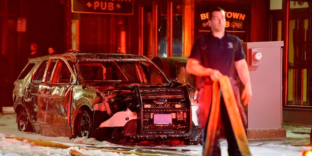 A firefighter stands near a police cruiser that was set on fire after clashes with protesters after a demonstration over the death of George Floyd, an unarmed black man who died in Minneapolis Police custody, in Boston, Massachusetts on May 31, 2020. (Photo by Joseph Prezioso/AFP via Getty Images)