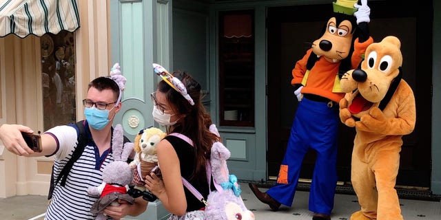 Tourists take a selfie with Disney characters at the Hong Kong Disneyland on Sept. 25, one of the theme park's grand reopening days this year. (Photo by Chen Qiman/Xinhua via Getty) (Xinhua/Chen Qiman via Getty Images)