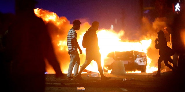 Demonstrators walk in front of a police car that has been lit on fire during a protest in response to the recent death of George Floyd on May 31, 2020 in Boston, Massachusetts. Protests spread across cities in the U.S., and in other parts of the world in response to the death of African American George Floyd while in police custody in Minneapolis, Minnesota. (Photo by Maddie Meyer/Getty Images)