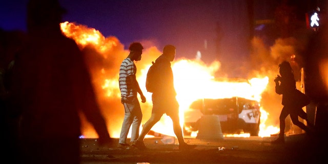 Demonstrators walk in front of a police car that has been lit on fire during a protest in response to the recent death of George Floyd on May 31, 2020 a Boston, Massachusetts. Protests spread across cities in the U.S., and in other parts of the world in response to the death of African American George Floyd while in police custody in Minneapolis, Minnesota. (Foto di Maddie Meyer / Getty Images)