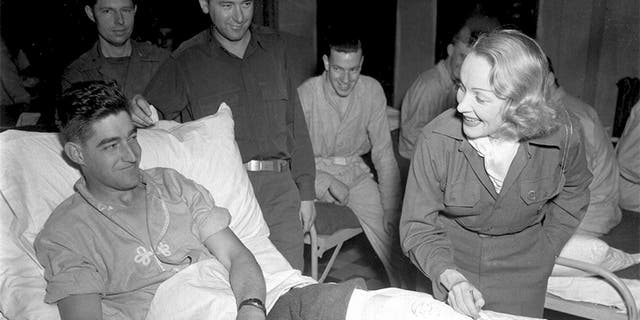 Marlene Dietrich meets a wounded soldier from Texas at a United States hospital in Belgium, November 1944.