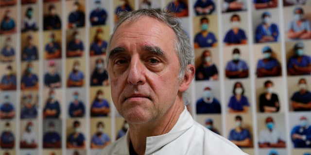 Dr. Philippe Montravers poses in front of a collection of portraits of medical staff at Bichat Hospital, AP-HP, in Paris.