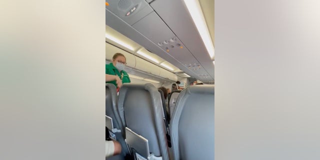 An airline employee can be seen, on the left, asking the seated passenger to comply with the airline's mask policy.  (Kelsi Harris)