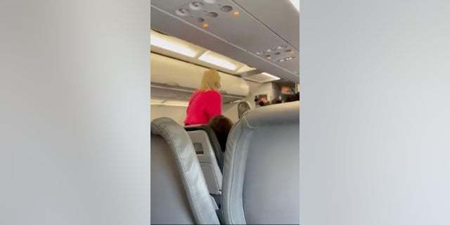 Passengers were heard clapping, and one called her "Karen," as she was escorted from the plane.  (Kelsi Harris)