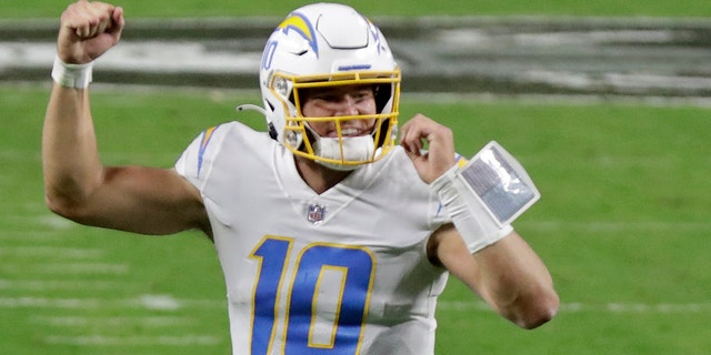 Los Angeles Chargers quarterback Justin Herbert (10) celebrates after running back Kalen Ballage scored a touchdown against the Las Vegas Raiders during the second half of an NFL football game, Thursday, Dec. 17, 2020, in Las Vegas. (AP Photo/Isaac Brekken)