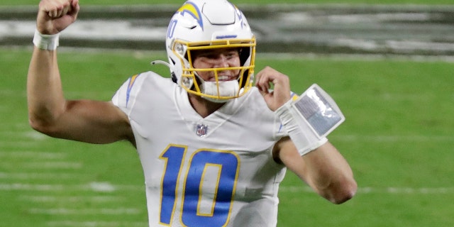 Los Angeles Chargers quarterback Justin Herbert (10) celebrates after running back Kalen Ballage scored a touchdown against the Las Vegas Raiders during the second half of an NFL football game, Thursday, Dec. 17, 2020, in Las Vegas. (AP Photo/Isaac Brekken)