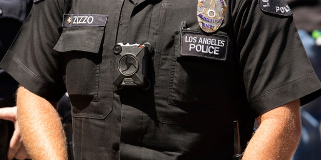 A Los Angeles police officer wearing a body camera stands watch outside of City Hall.