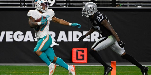 Miami Dolphins running back Myles Gaskin (37) scores a touchdown against Las Vegas Raiders cornerback Trayvon Mullen (27) during the second half of an NFL football game, Saturday, Dec. 26, 2020, in Las Vegas. (AP Photo/David Becker)