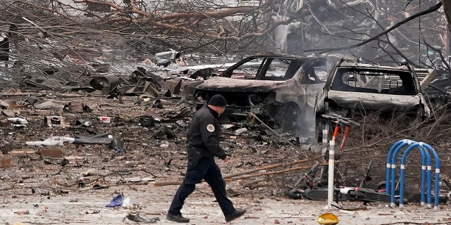 A law enforcement member walks past damage from an explosion in downtown Nashville, Tenn., Friday, Dec. 25, 2020. Buildings shook in the immediate area and beyond after a loud boom was heard early Christmas morning. (AP Photo/Mark Humphrey)