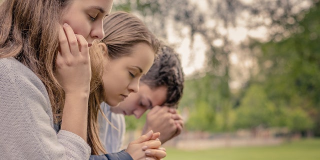 Happy friends are shown praying together in the park. "Please keep me safe. Please give me good friends," as one prayer says.