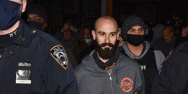 Mac's Public House co-owner Danny Presti is taken away in handcuffs after being arrested Tuesday by New York Sheriff's deputies in New York's Staten Island neighborhood.  Presti, who was providing service indoors in defiance of coronavirus restrictions, was arrested after an injection in which plainclothes officers entered and ordered food and drink.  (Steve White via AP)