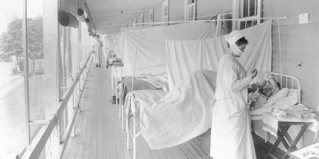 In this November 1918 photo made available by the Library of Congress, a nurse takes the pulse of a patient in the influenza ward of the Walter Reed hospital in Washington. In 1918, tens of thousands of U.S. soldiers died in World War I and hundreds of thousands of Americans died in a flu pandemic. Deaths rose 46% that year, compared with 1917. (Harris &amp; Ewing/Library of Congress via AP, File)