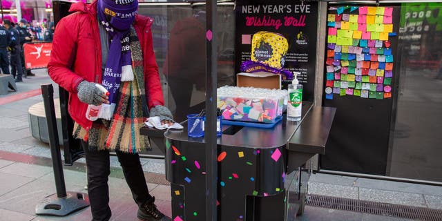 A worker in Times Square sanitizes the booth where people can write their new year wish on confetti that will shower the Crossroads of the World on New Year's Eve.