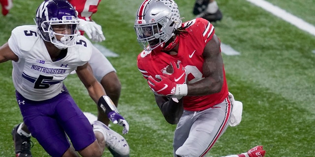 Ohio State running back Trey Sermon, right, scores past Northwestern defensive back JR Pace (5) during the second half of the Big Ten championship NCAA college football game, Saturday, Dec. 19, 2020, in Indianapolis. (AP Photo/Darron Cummings)