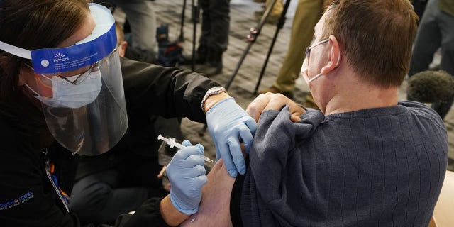 Dr. Chadi Ibrahim receives the Pfizer-BioNTech COVID-19 vaccine from Susan Grand at the Beaumont Service Center, Tuesday, Dec. 15, 2020 in Southfield, Mich. (AP Photo/Carlos Osorio)