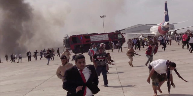 People run following the explosion at Aden airport. At least 16 have been reported dead. (AP)