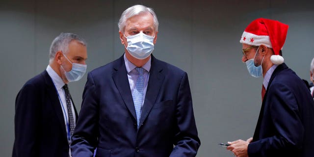 A colleague wears a Christmas hat as European Union chief negotiator Michel Barnier, center, carries a binder of the Brexit trade deal during a special meeting of Coreper, at the European Council building in Brussels, on Dec. 25. (AP)