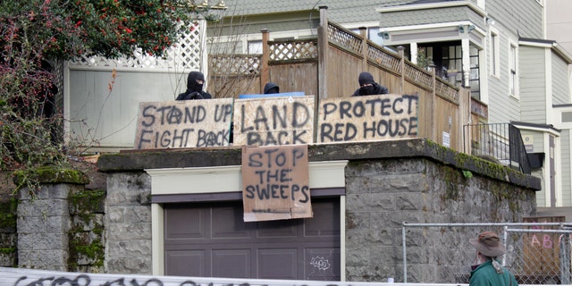 Masked protesters by an occupied house speak to a neighborhood opposed to their camp and protest in Portland, Ore., On Wednesday, December 9, 2020. Cross barricades erected by protesters are still in the largest city of Oregon a day after Portland police were arrested.  about a dozen people in a clash over gentrification and the eviction of a family from a home.  (AP Photo / Gillian Flaccus)