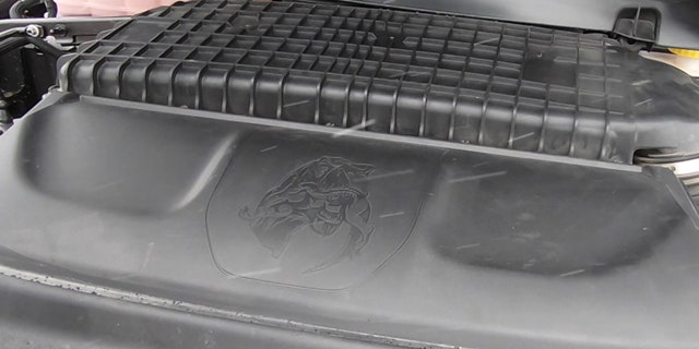 The Ram 1500 TRX's engine cover has an image of a T. rex with a raptor in its mouth.