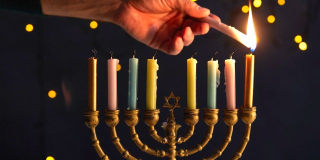 A man lights up the candles of a menorah for Hanukkah