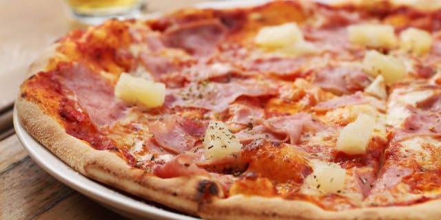 Close-up of pizza with ham and pineapple.