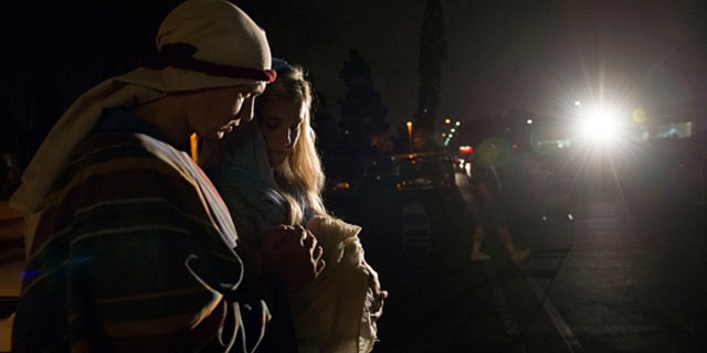 Church members carry their baby as they walk to the manger as Joseph and Mary outside the Church of Jesus Christ in Fountain Valley, California, Dec. 10, 2015.