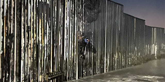 The 25-year-old Mexican national was spotted hanging from part of the wall that jutted out into the Pacific Ocean, the agency said.