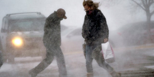 A shopper returns to her vehicle in blowing snow in Omaha, Neb., Woensdag, Des. 23, 2020. (AP Photo/Nati Harnik)