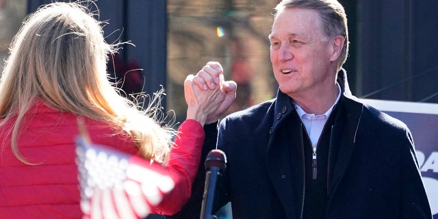 Sen. David Perdue, R-Ga., and Sen. Kelly Loeffler, R-Ga., clasp hands during a campaign rally, Monday Dec. 21, 2020, in Milton, Ga. (AP Photo/John Bazemore)