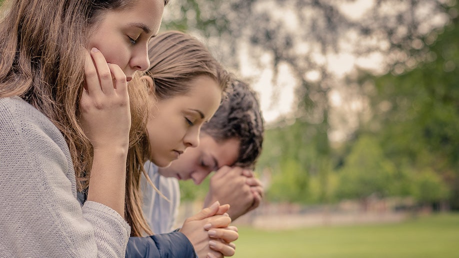 Kids praying outside with hands folded