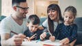 Two parents and a little boy drawing and writing together (iStock)