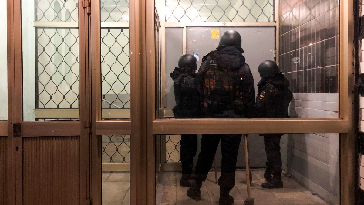 Police stand in front of a door of the apartment building where Oleg Navalny, brother of jailed opposition leader Alexei Navalny lives in Moscow, Russia, Wednesday, Jan. 27, 2021. Police are searching the Moscow apartment of jailed Russian opposition leader Alexei Navalny, another apartment where his wife is living and two offices of his anti-corruption organization. Navalny's aides reported the Wednesday raids on social media. (AP Photo/Mstyslav Chernov)