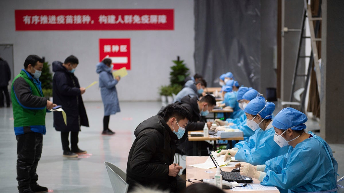 In this photo released by Xinhua News Agency, residents fill out content forms before receiving their COVID-19 vaccinations at a temporary vaccination site in Beijing, Saturday, Jan. 2, 2021. China authorized its first homegrown COVID-19 vaccine for general use on Dec. 31, 2020, adding another shot that could see wide use in poorer countries as the virus surges back around the globe. (Chen Zhonghao/Xinhua via AP)