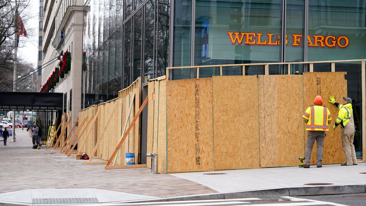 Workers board up buildings near Freedom Plaza in downtown Washington, Monday, Jan. 4, 2021, in preparation for a rally on January 6, the day when Congress is scheduled to meet to formally finalize the presidential election results.