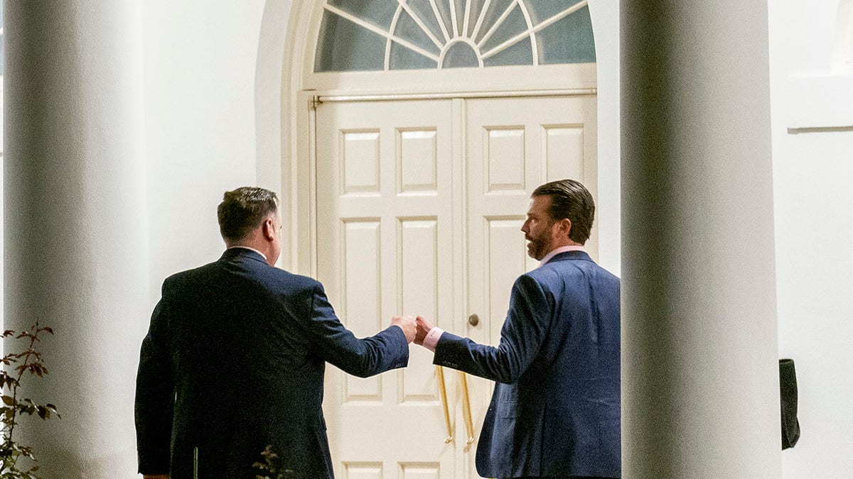 White House social media director Dan Scavino, left, greets Donald Trump Jr., the son of President Donald Trump, after taking a photo of him along the Colonnade toward the West Wing in the early morning hours at the White House in Washington. (AP Photo/Andrew Harnik)
