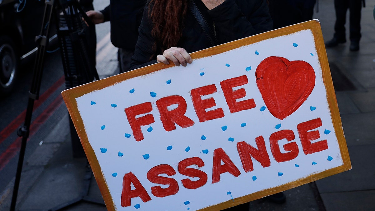 A Julian Assange supporter holds a poster outside the Westminster Magistrates Court after he was denied bail at a hearing in the court in London, Wednesday, Jan. 6, 2021. (AP Photo/Matt Dunham)