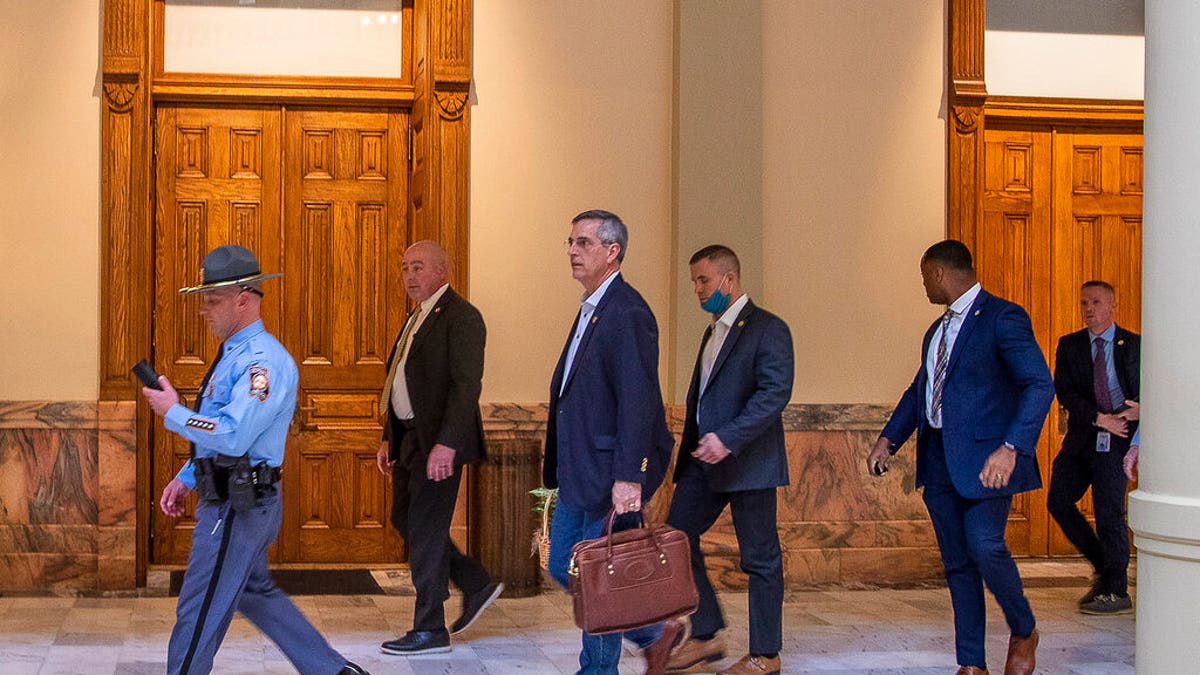 Lead by a Georgia State Trooper, Georgia Secretary of State Brad Raffensperger, center, exits the Georgia State Capitol building after hearing reports of threats, Jan. 6, in Atlanta. 