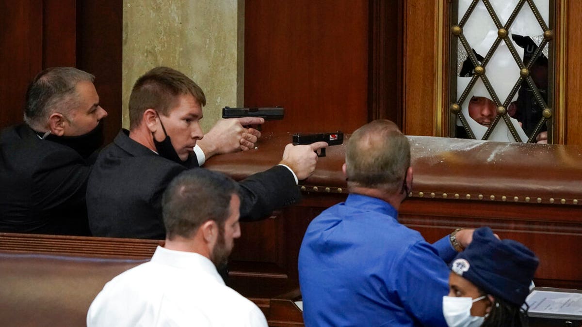 U.S. Capitol Police with guns drawn watch as protesters try to break into the House Chamber at the U.S. Capitol on Wednesday, Jan. 6, 2021, in Washington. (AP Photo/J. Scott Applewhite)