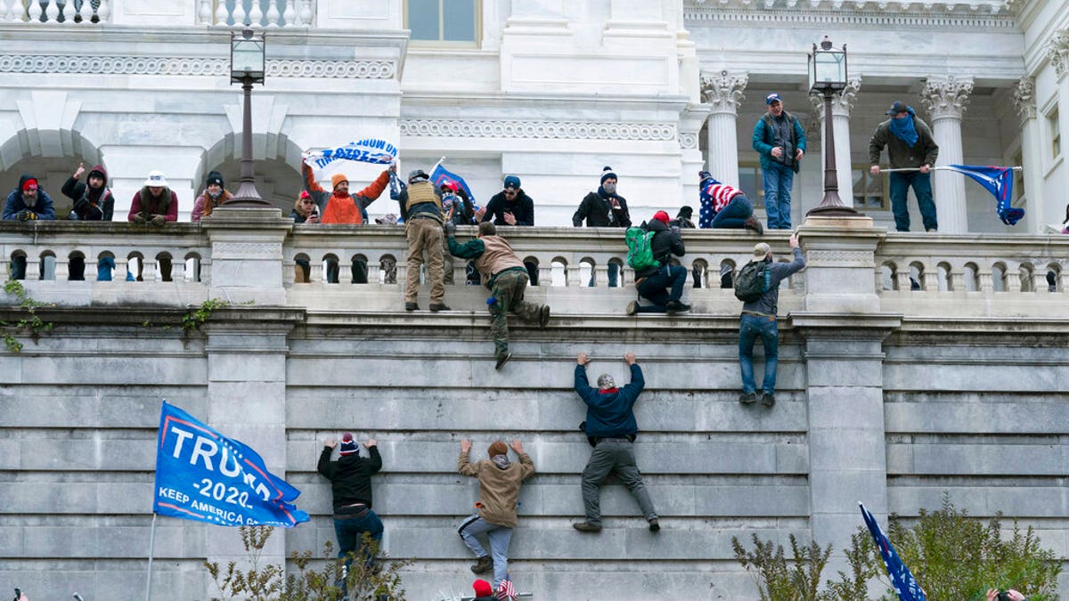 Supporters of President Donald Trump climb the west wall of the the U.S. Capitol on Wednesday, Jan. 6, 2021, in Washington. (AP Photo/Jose Luis Magana)