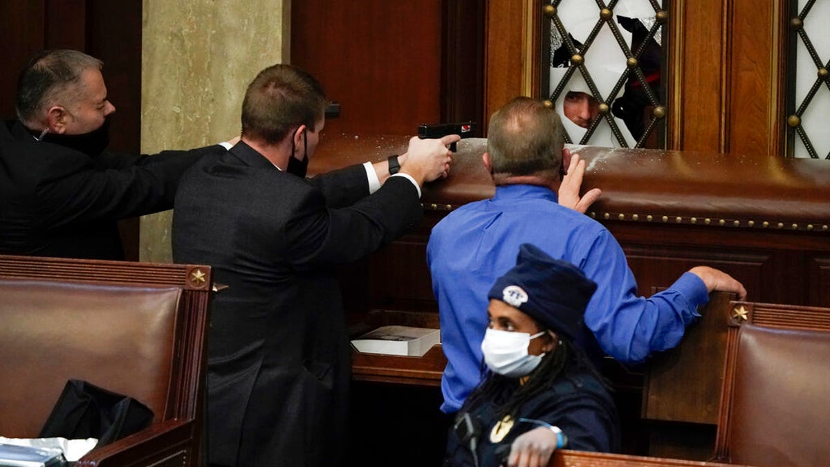 Police with guns drawn watch as protesters try to break into the House Chamber at the U.S. Capitol on Wednesday, Jan. 6, 2021, in Washington. (AP Photo/J. Scott Applewhite)
