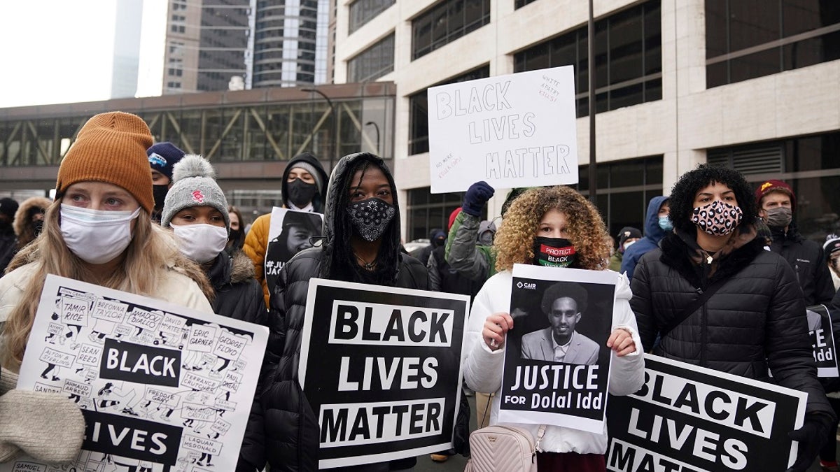 Black Lives Matter protesters, including Markeanna Tyus, center left, and Isis Atallah, center right, stand in the middle of 3rd Avenue South as they prepare to march from the Hennepin County Government Center to demand justice for Jacob Blake. (Anthony Souffle/Star Tribune via AP)