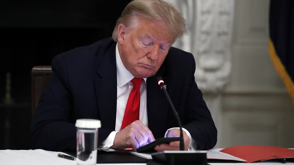 In this Thursday, June 18, 2020, file photo, President Donald Trump looks at his phone during a roundtable with governors on the reopening of America's small businesses in the State Dining Room of the White House in Washington. Trump this week could become the only president to ever be impeached twice. (AP Photo/Alex Brandon, File)