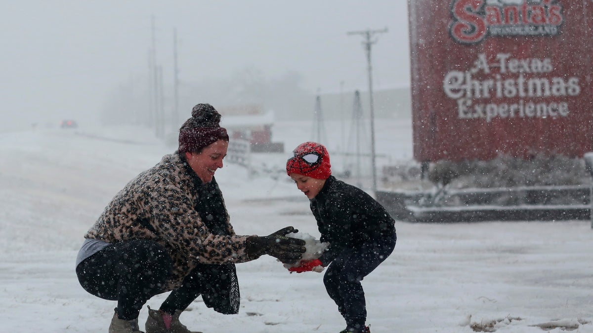 Heather makes a snowball and hands it to her son, Weston, 5, to build a snowman at Santa's Wonderland on Highway 6 Sunday, Jan. 10, 2021, in College Station, Texas. The family of five drove up from Waller to find snow. (Yi-Chin Lee/Houston Chronicle via AP)