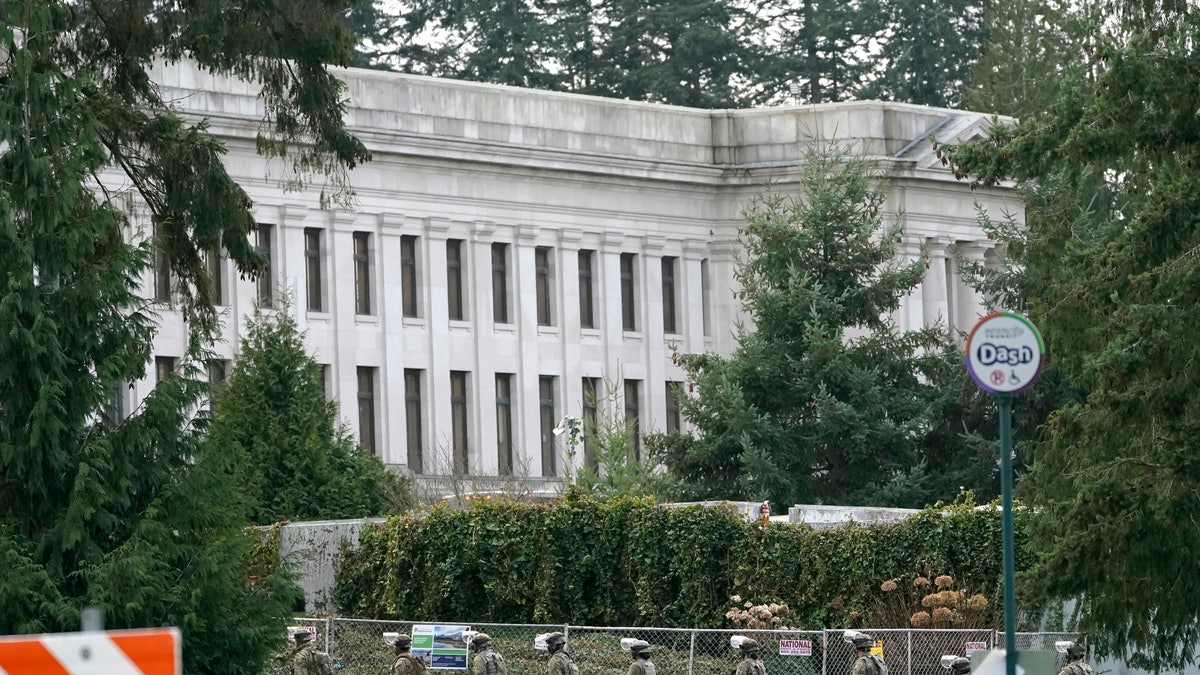 National Guard members march near a perimeter fence, Sunday, Jan. 10, 2021, at the Capitol in Olympia, Wash. Washington Gov. Jay Inslee activated members of the National Guard this week to work with the Washington State Patrol to protect the Capitol campus. A small rally with speakers, flags and signs representing several groups was held near the fence Sunday, but most attendees had left by early evening. (AP Photo/Ted S. Warren)