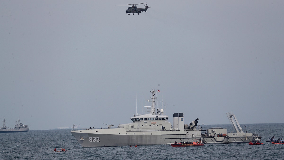 A military helicopter flies past as Indonesian Navy ships continue their search for the wreckage of Sriwijaya Air passenger jet that crashed into Java Sea near Jakarta, Indonesia, Monday, Jan. 11, 2021. Indonesian navy divers scoured the floor of the Java Sea on Monday as they hunted for the black boxes of a Sriwijaya Air jet that nosedived into the waters at high velocity with dozens of people aboard. (AP Photo/Tatan Syuflana)