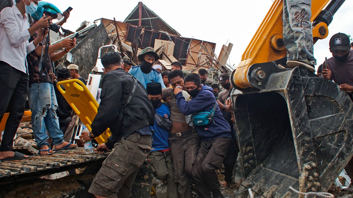 Rescuers assist a survivor pulled out from the ruin of a government building that collapsed during an earthquake in Mamuju, West Sulawesi, Indonesia, Friday, Jan. 15, 2021. (AP Photo/Azhari Surahman)